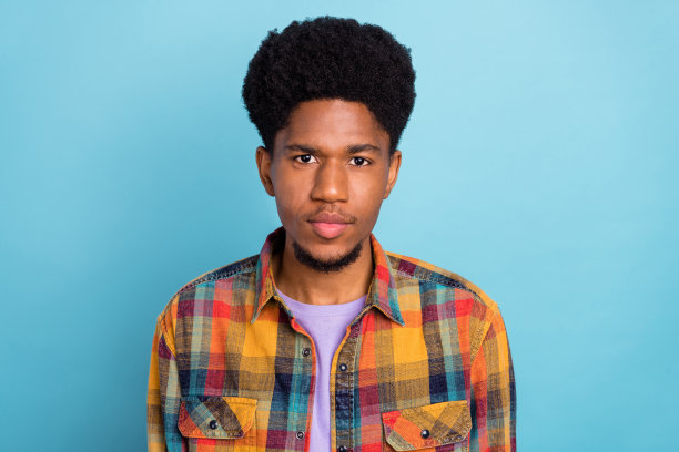 照片：身穿紫色T恤、大眼睛、皮肤黝黑的漂亮小伙子，脸上露出惊讶的表情，背景为纯蓝色。图片下载