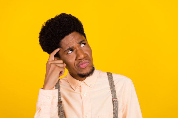 照片：一个傻乎乎的疯狂男人，鬼脸吐舌，眯着眼睛，穿着背带衬衫，在黄色的背景下图片下载