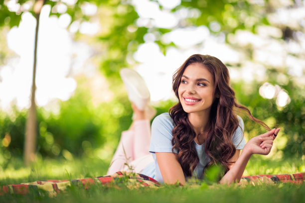 照片：一位快乐、可爱、充满梦想、积极的年轻女子在周末的户外公园里享受大自然并微笑图片下载