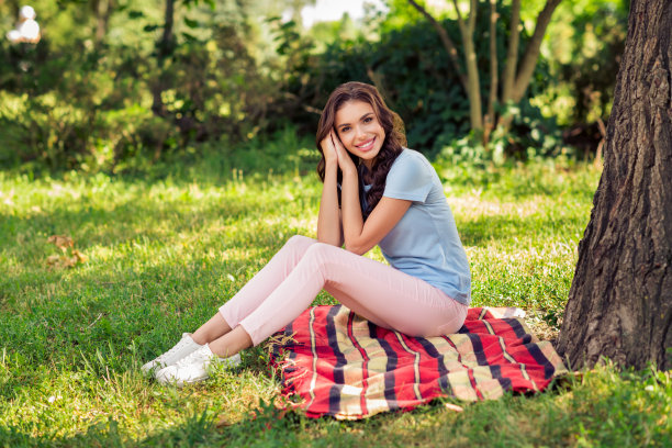 照片：一位快乐、可爱、爱幻想、积极的年轻女子在户外公园享受周末的笑容图片下载