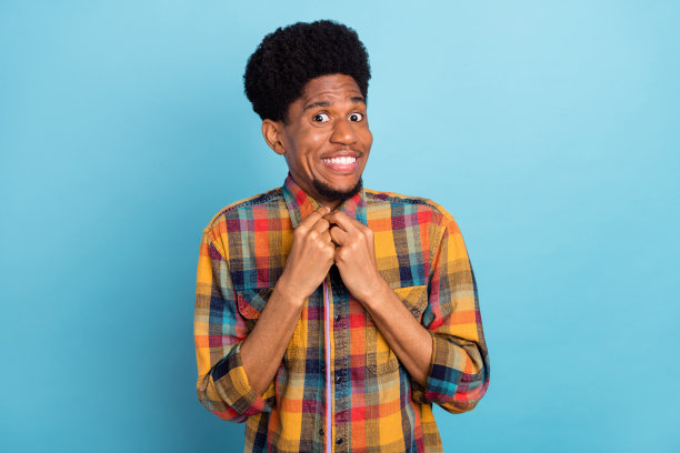 照片：身穿紫色T恤、大眼睛、深肤色的漂亮男子，表情惊讶，背景为蓝色。图片下载