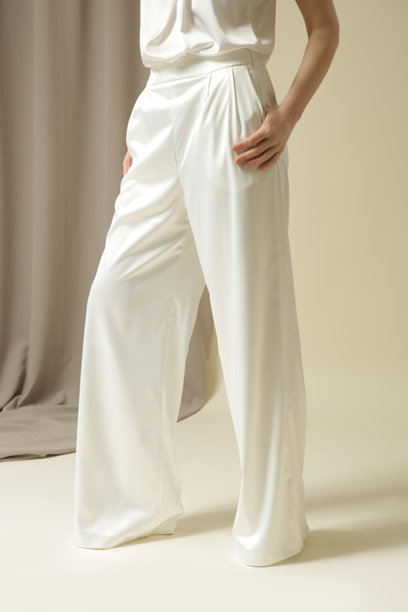 女模特身穿白色缎面阔腿裤的棚拍照片。图片下载