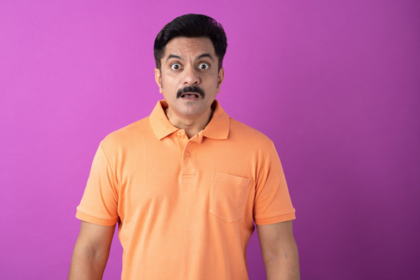 身穿橙色T恤的印度中年男子，在紫色背景下隔离的照片素材图片下载