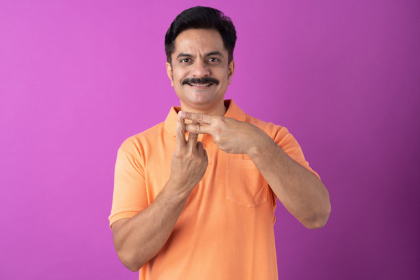 身穿橙色T恤的印度中年男子，孤立在紫色背景上的照片图片下载