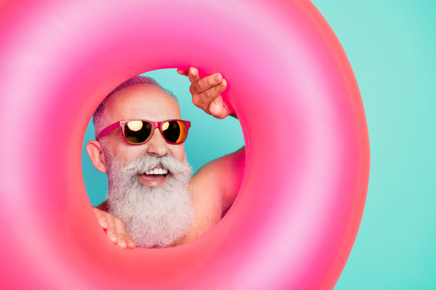 照片：成功的、运动健将、肌肉发达的爷爷展示强壮的双手，身穿粉色短裤，背景为孤立的绿松石色图片下载