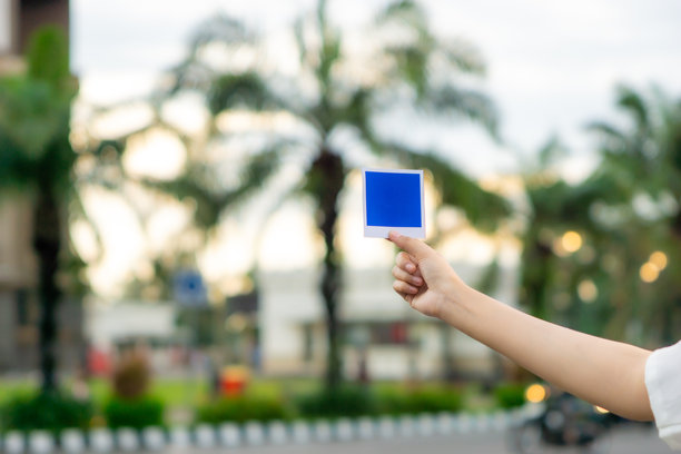 手里拿着蓝色的宝丽来照片纸在街上，一台老式相机。图片下载