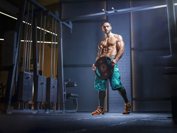 健美男士。一位身材健美的年轻男子在现代健身房锻炼。运动。健身与健康概念。健美男子在运动。肌肉健美模特使用哑铃和杠铃锻炼的照片图片下载