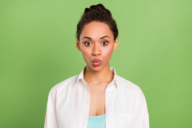 照片肖像，一名女子穿着白色衬衫，惊讶地笑着，背景是粉绿色的纯色图片下载