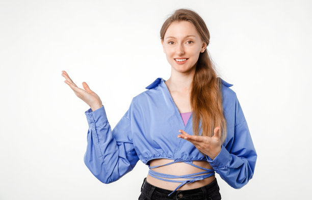 一位穿着休闲装的快乐年轻女子，站在白色背景前，自信地指向适合广告、信息、标语或图形插入的空白空间，工作室照片图片下载