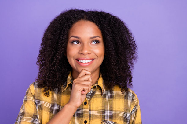 照片：一个肤色黝黑、表情担忧、不开心、沮丧的女人咬着嘴唇，情绪不佳，孤立在紫色背景上图片下载