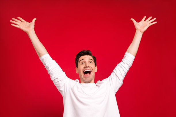 照片肖像：惊讶的棕发女子穿着休闲T恤，脸上洋溢着快乐的笑容，在明亮的红色背景前。图片下载