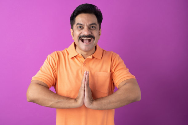 照片：身穿橙色T恤的印度中年男子，孤立在紫色背景上图片下载