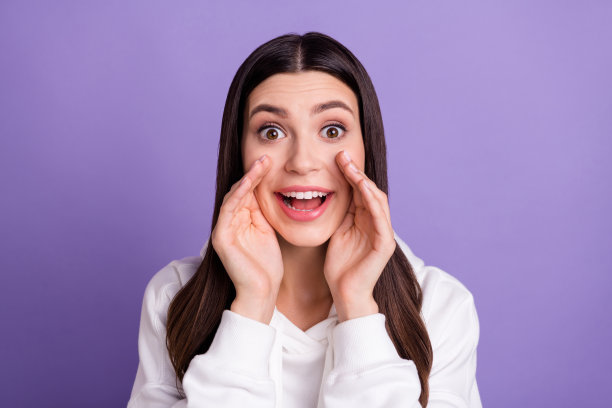 照片：一位心情愉悦、面带惊喜微笑的女性，面部表情激动，背景为紫色图片下载