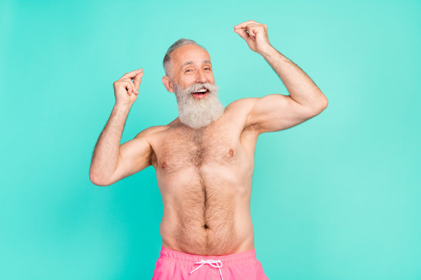照片：一位成功的、健壮的、肌肉发达的爷爷展示着强壮的手，穿着粉色短裤，背景是孤立的青色图片下载