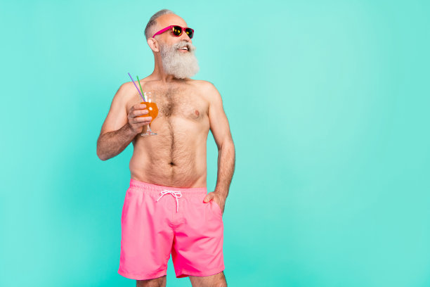 照片：身穿粉色短裤、肌肉发达、运动健将的成功爷爷，展示强壮的双手，背景为孤立的青绿色图片下载