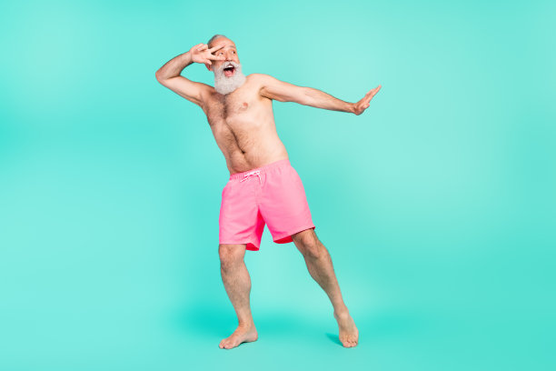 照片：一位成功的、健壮的、肌肉发达的爷爷展示着强有力的双手，身穿粉色短裤，背景为孤立的青色图片下载