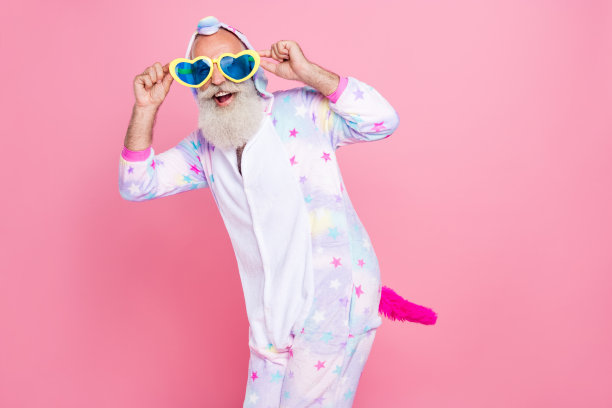 身穿连体睡衣和袜子，摆出飞机姿势，孤立在粉色背景上的退休疯狂艺术家照片图片下载