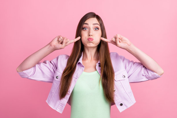 照片肖像：一位戴着休闲衬衫的女性，在粉色背景前送出飞吻，她在约会，背景为粉色。图片下载