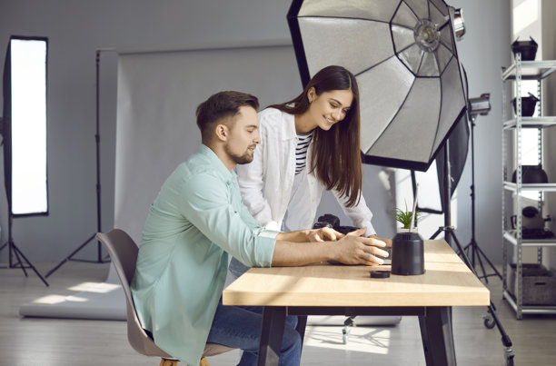 两位快乐的年轻摄影师在工作室里看着笔记本电脑上的照片图片下载