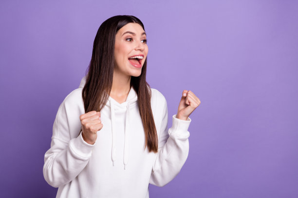 照片：一位快乐、喜悦、惊奇、兴奋、心情愉悦、面带微笑、对新闻做出反应的女性，孤立在紫色背景上图片下载