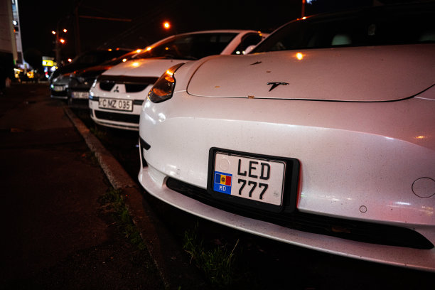 摩尔多瓦基希讷乌的夜晚街道，一辆白色特斯拉LED 777停在路灯下的汽车之间图片下载