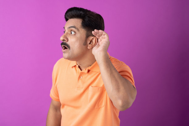 身穿橙色T恤的印度中年男性照片，孤立在紫色背景上图片下载