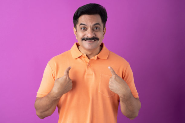 印度中年男子身穿橙色T恤，在紫色背景下拍摄的照片图片下载