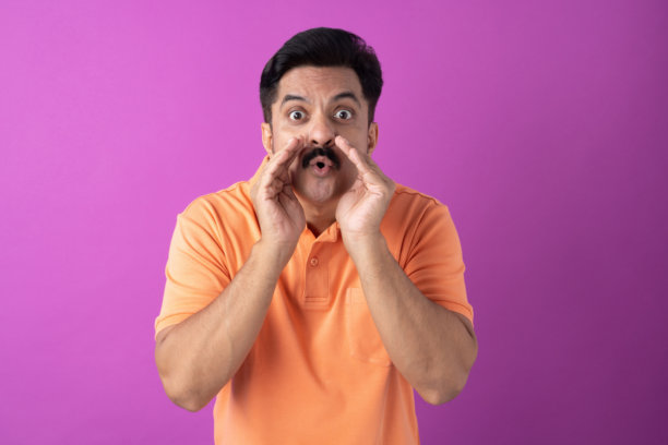 身穿橙色T恤的印度中年男性照片，孤立在紫色背景上图片下载