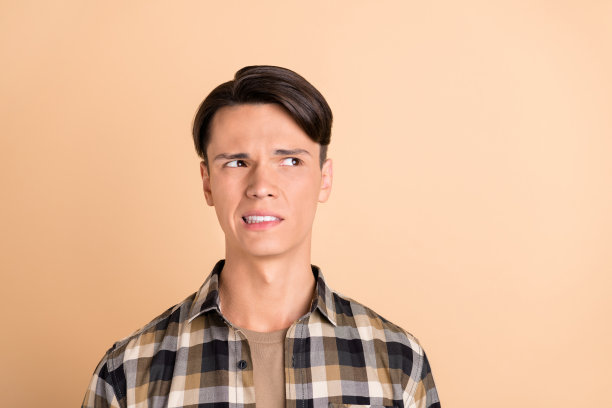 身穿格子衬衫的千禧一代帅气男士照片，孤立在米色背景上图片下载