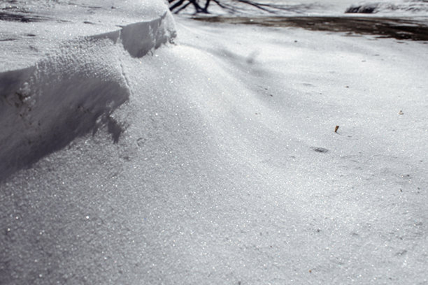 阳光下雪堆的特写照片，突出了闪闪发光的雪晶和纹理。冬季天气背景，留有复制空间。图片下载