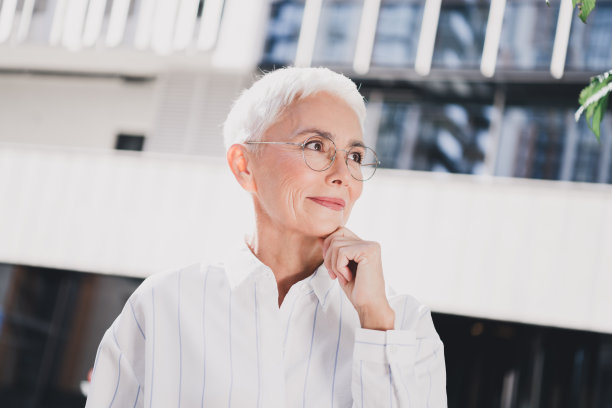 一位穿着时尚条纹白衬衫的专业成熟的女性，在城市景观中若有所思，适合商业生活方式的图库图片图片下载