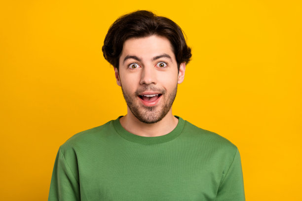 照片：一个张着嘴、露出OMG表情的开心兴奋的疯狂男子，穿着绿色套头衫，背景是黄色的孤立色图片下载