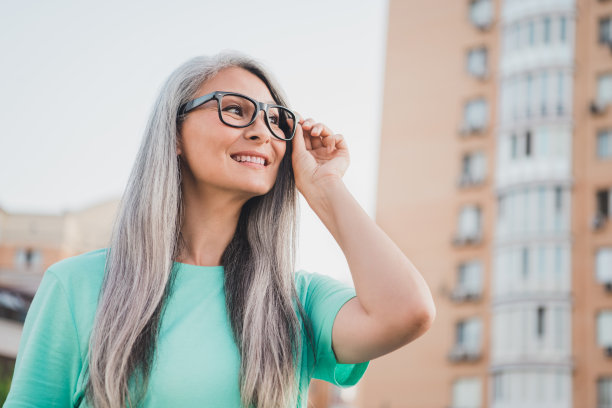 照片：一位梦想着、思考着的创意退休女士，穿着蓝色T恤，在城市户外望着晴朗的天空。图片下载