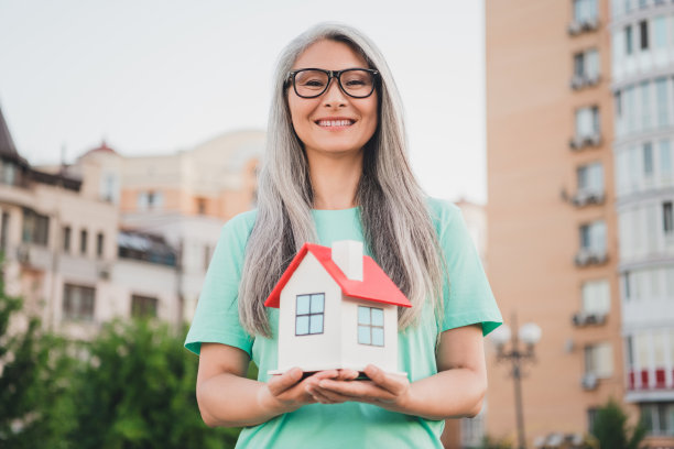照片：一位梦想着、思考着、富有创意的退休女士，穿着绿松石色T恤，望着城市外的晴朗天空。图片下载