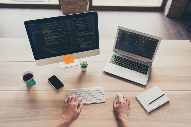 特写照片，年轻男子的手正在使用电脑键盘，电脑显示器屏幕上显示着代码，正在室内进行软件测试和在线编程。图片下载