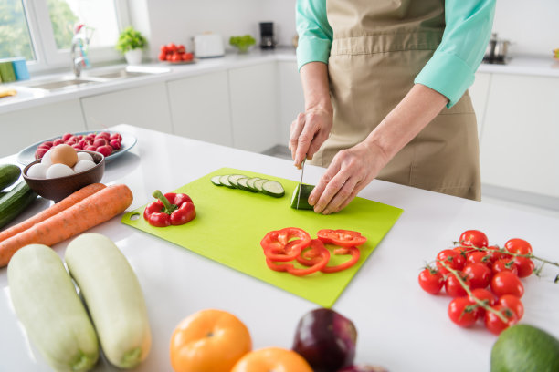 俯视角度拍摄的成熟快乐女厨师在厨房做早餐的照片，她穿着围裙，在室内。图片下载