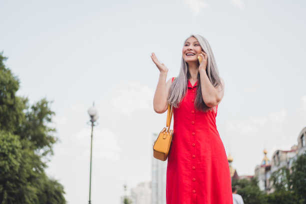 照片：一位成熟迷人的亚洲女性，带着开心的积极笑容，在夏季户外市中心散步，享受旅程和假期。图片下载
