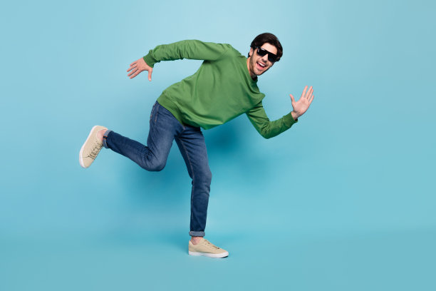 身着太阳镜的年轻帅气小伙子，心情愉悦，在蓝色背景前玩闹，照片为全尺寸。图片下载