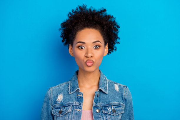 照片：一位快乐、时髦、精神焕发的年轻女子，表情俏皮，背景为蓝色图片下载