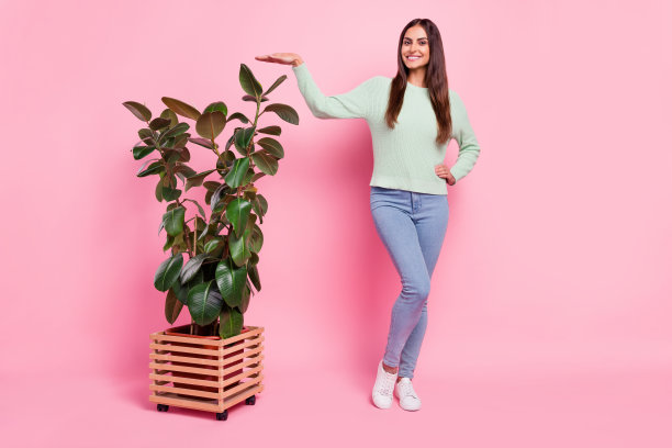 身穿绿色套头衫的可爱千禧一代棕发女士，在粉色背景上拍摄的照片图片下载