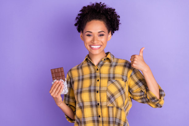 照片：一个快乐积极微笑的非洲小女孩，吃着棉花糖，节食，卡路里，孤立在紫色背景上图片下载