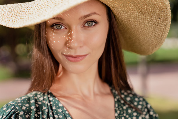 照片：一位面带灿烂笑容、眼神望向一侧的迷人女友，手放在胸前，置身于自然公园的户外花园中。图片下载