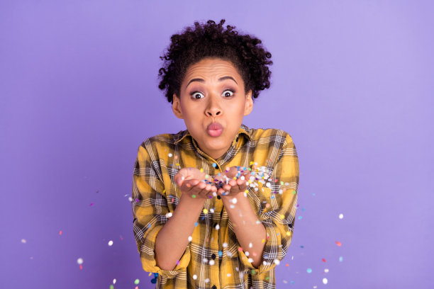 照片：一个快乐、积极微笑的非洲小女孩，吃着棉花糖，无视饮食热量，孤立在紫色背景上。图片下载