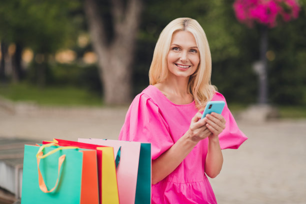 一位穿着粉色服装、笑容可掬的退休女士在城市街道上散步的有趣照片图片下载