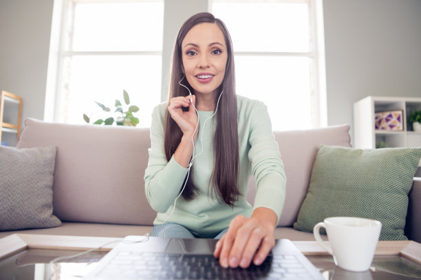 照片：可爱的年轻棕发女士独自在家，穿着蓝色衬衫坐在沙发上图片下载