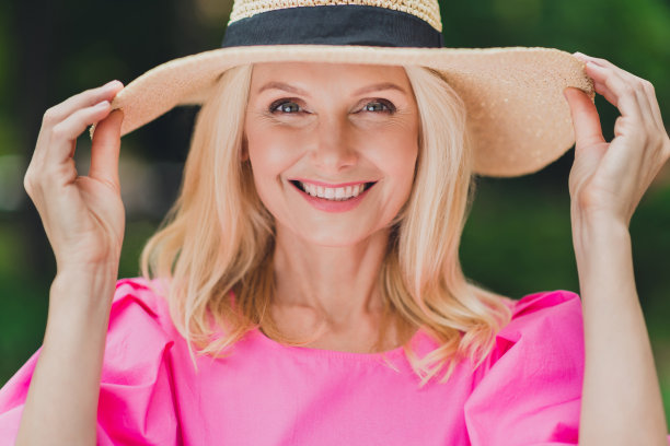 照片：一位穿着粉色衣服、面带笑容的可爱退休女士在城市街道上行走图片下载