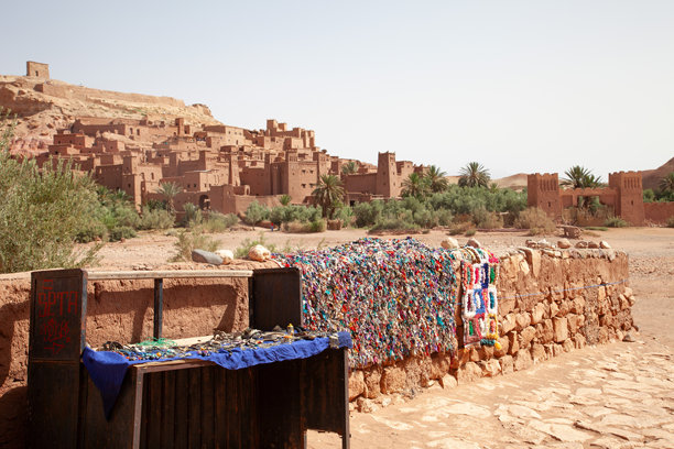 艾特·本·哈杜联合国教科文组织遗址的摩洛哥传统手工艺品摊位，背景为古老的城堡，售卖正宗纪念品和色彩鲜艳的地毯，摩洛哥，艾特·本·哈杜的当地手工艺品市场，展示手工珠宝和纺织品图片下载