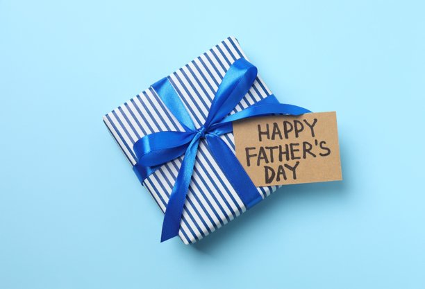 父亲节快乐。蓝色背景上带有丝带蝴蝶结的礼品盒俯视照片图片下载