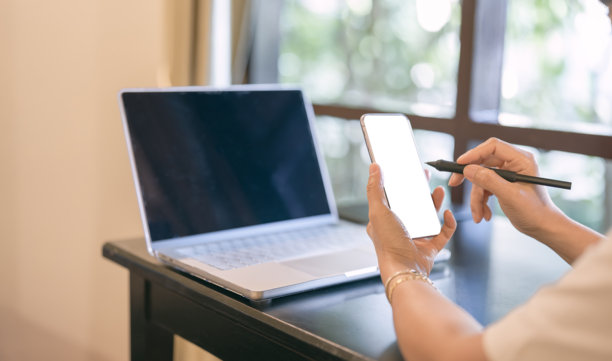 白色背景下智能手机的肩膀视角模糊的笔记本电脑背景样机图片下载