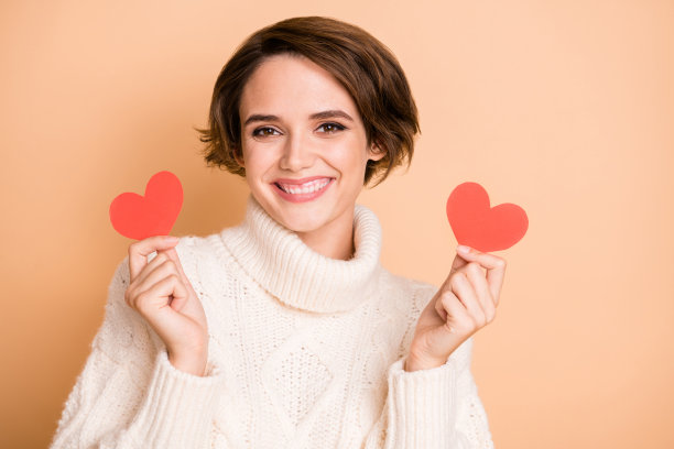 照片肖像：一位留着短发的漂亮女孩，穿着休闲的冬季保暖毛衣，在柔和的米色背景上。图片下载